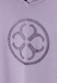 Felpa viola lavanda con un logo circolare ricamato e testurizzato di tonalità più scura, centrato sul fronte. Tessuto liscio con un design casual.