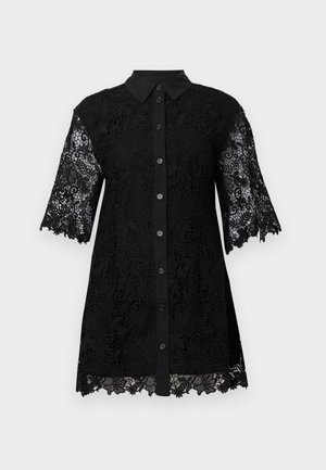Camisa negra de encaje con botones y cuello, con mangas cortas y patrones florales. El dobladillo tiene un borde festoneado.
