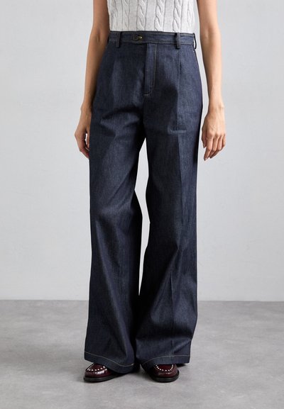 Donkerblauwe wijde denim broek met een hoge taille, voorzien van gouden stiksels en een knopenfrontsluiting. Soepele, casual textuur.