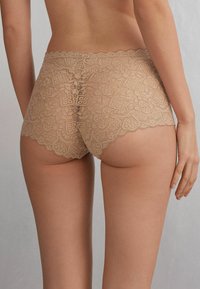 Lace boyshorts in een nude kleur met een bloemenpatroon en golvende randen, voorzien van een lage taille en een elastische tailleband voor comfort.