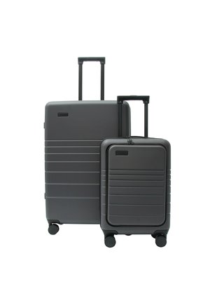 Zwei dunkelgraue Hartschalenkoffer mit ausziehbaren Griffen und vier Rollen, ein größerer hinter einem kleineren, vor weißem Hintergrund.