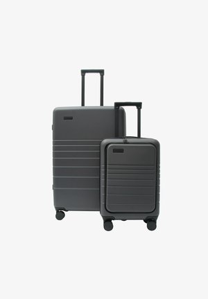 Zwei dunkelgraue Hartschalenkoffer mit ausziehbaren Griffen und vier Rollen, ein größerer hinter einem kleineren, vor weißem Hintergrund.