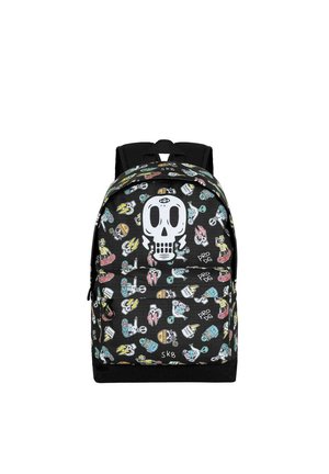 Mochila negra con un gráfico de calavera blanca, cubierta de coloridas pegatinas. Presenta correas ajustables y compartimentos con cremallera.