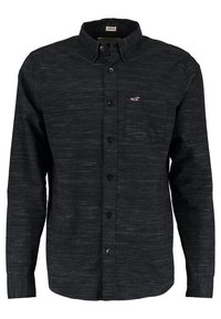 Svart långärmad skjorta med knappar i ett texturerat tyg, med krage, bröstficka och en liten logotyp på vänster sida.