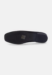 Chaussure plate noire avec une tige en suede lisse et une semelle en caoutchouc texturée. Présente une pointe arrondie et un design minimaliste.