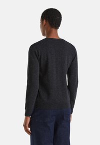 Pull en tricot gris foncé avec un col rond et des manches longues, présentant une légère texture côtelée aux poignets et à l'ourlet. Vue de dos montrée.