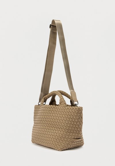 Πλεκτή μπεζ τσάντα χειρός με διπλά χερούλια, ρυθμιζόμενο λουράκι και υφή με μοτίβο. Διαθέτει μικρή τσέπη στο πλάι. Συμπαγής σχεδιασμός.