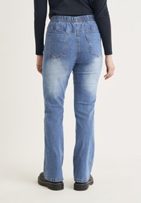 Ljusblå denimjeans med elastiskt midjeband, rak benstil, två bakfickor och en urtvättad finish vid låren och vaderna.