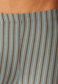 Gestreifter Stoffbund in Grau mit weißen und orangen Streifen, der eine glatte Textur und eine ordentliche Naht entlang der Kanten aufweist.