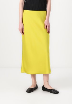Gonna midi gialla realizzata in tessuto morbido, con vita aderente e linea fluida, abbinata a ballerine nere. Design semplice e elegante.