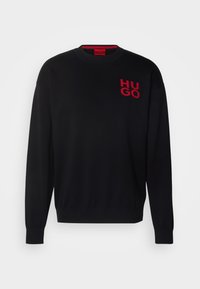 Pull noir avec poignets et encolure côtelés. Présente un logo rouge "HUGO" sur le côté gauche de la poitrine. Confectionné en tissu tricoté lisse.