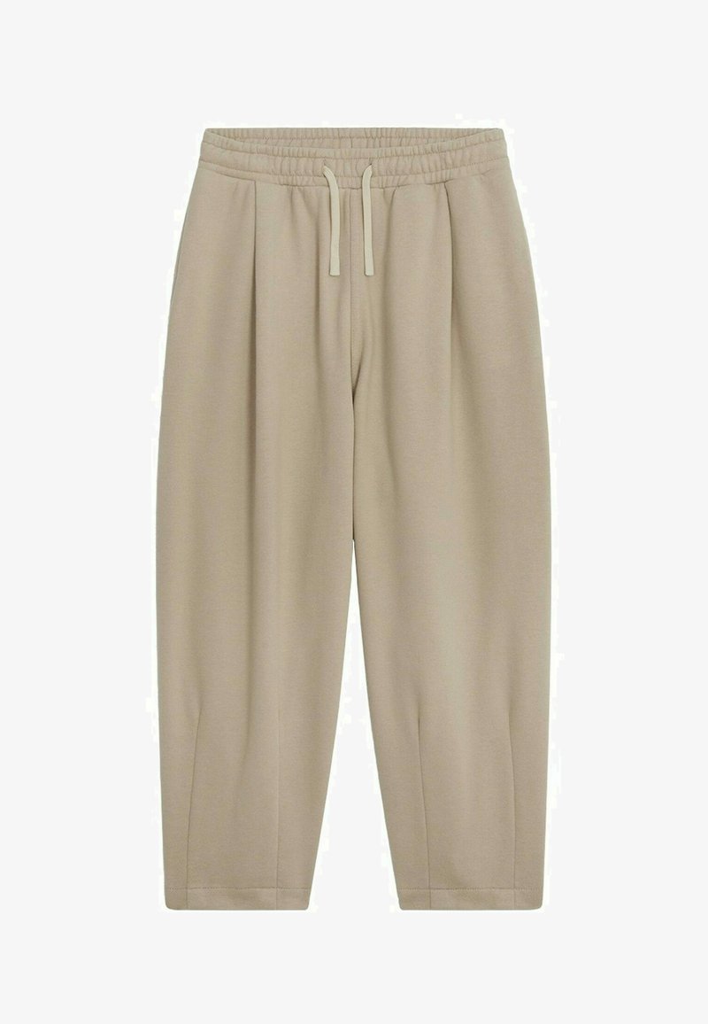Pantalon de survêtement beige au fit décontracté, avec une taille élastique, un cordon de serrage et des chevilles fuselées. Fabriqué en tissu doux et lisse avec des plis sur les côtés.