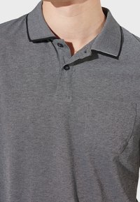 Polo gris avec un tissage texturé, col à carreaux contrastant, patte de boutonnage à trois boutons et une poche poitrine sur le côté gauche.