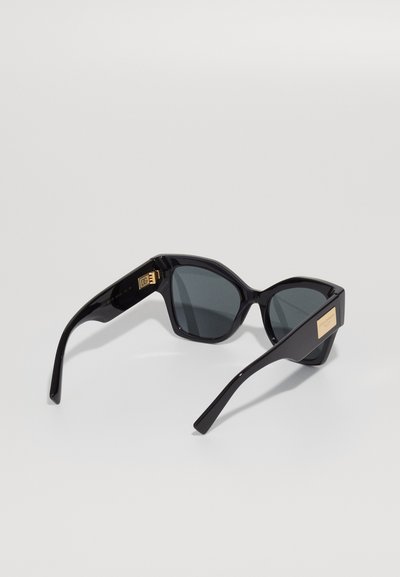 Ochelari de soare negri cu rame unghiulare, lentile întunecate și accente aurii pe temple. Finisaj din plastic lucios cu detalii de design elegante.