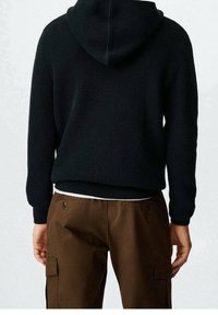 Hoodie noir en maille à surface texturée avec capuche, associé à un pantalon cargo marron avec poches latérales et coupe décontractée.