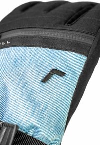Strukturiertes schwarzes Gewebe und hellblauer Denim verbinden sich in einem gepolsterten Handschuh mit einem Reißverschluss und einem kleinen schwarzen Emblem auf dem Denim-Bereich.