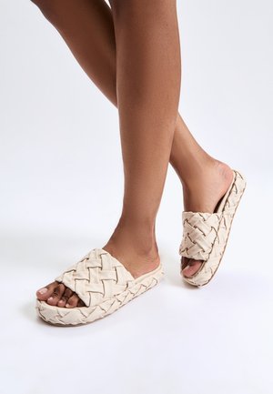 Sandali scivolati beige intrecciati con una suola rialzata simile al sughero e design con punta aperta, caratterizzati da un motivo in tessuto testurizzato.