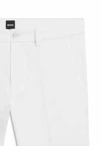 Pantalones blancos a medida con bolsillos laterales, cierre de botón y cremallera, trabillas para cinturón y una etiqueta negra con la marca "BOSS" en el interior de la pretina.