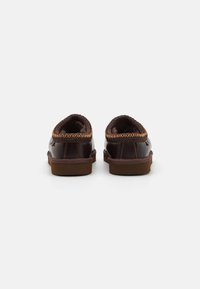 Brown leather slip-on shoes featuring a textured, woven trim and a rubber sole. The design is rounded at the toe and heel.