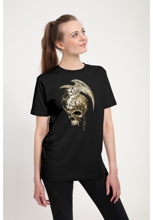 Młoda kobieta w czarnej koszulce z wzorem przedstawiającym skrzydlatą postać siedzącą na dużej czaszce z kropelkami.
