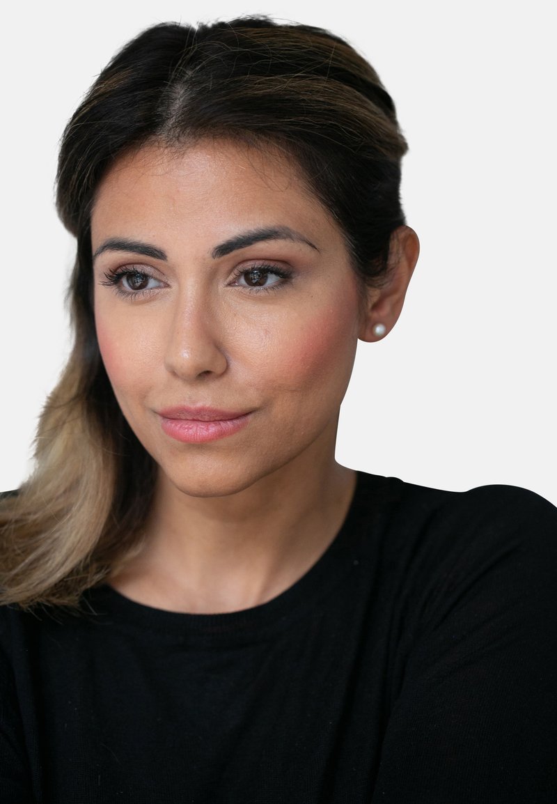 Nærbilde av en person med middels hudtone, mørkt hår og iført en svart topp. Kjennetegn inkluderer lett øyemakeup og perleøredobber.