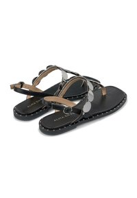 Zwarte platte sandalen met een gladde afwerking, voorzien van spiegelachtige ronde accenten en een gestikte rand. Verstelbare enkelriem voor een veilige pasvorm.