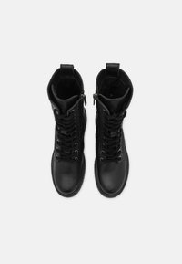 Bottes en cuir noir à la cheville avec une surface texturée, dotées de lacets traditionnels, de zips sur les côtés et d'un design à bout arrondi.