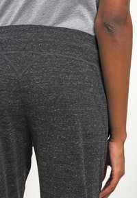 Grå ljung leggings med ett slätt, strukturerat tyg, hög midja och subtila sömnadsdetaljer, som sitter nära kroppen från midjan till vristen.