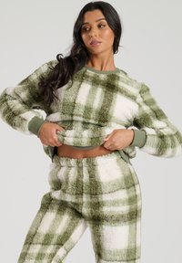 Green and white plaid fleece loungewear set, with a soft, fluffy texture. Features a crew neck sweatshirt and elastic waistband pants.