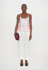 Satin rosa cami, hvite lin bukseseler med vid ben, og svarte leiligheter. Holder en rund burgunder clutch. Enkelt design, lett tekstur.
