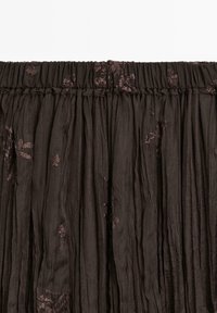 Dark brown pleated fabric with floral embroidery details along the top elastic waistband, featuring a lightweight and textured appearance.