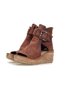 Brune læder wedge-sandaler med åbne tå, udskårne sider og brede ankelremme med store metalspænder.