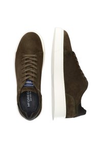 Sneaker in suede marrone con suole in gomma bianca, dotati di accenti verdi sui lacci e sul tallone, punta arrotondata e texture liscia.