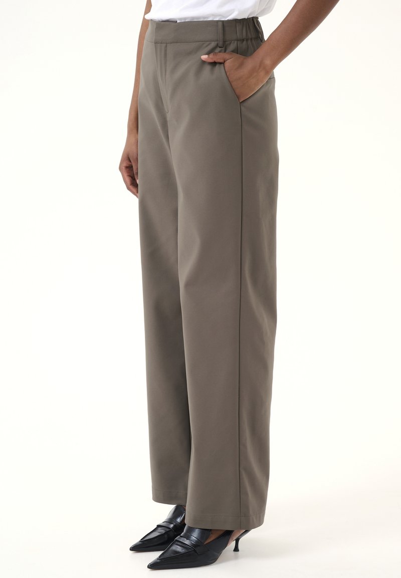Pantaloni cu picioare largi într-o nuanță de măslin atenuat, cu o textură netedă, buzunare laterale și un elastic confortabil la talie.