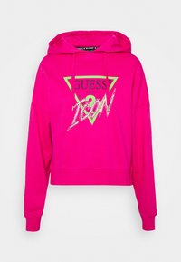 Sudadera cropped rosa con un logo triangular en la parte frontal de color verde y negro, que presenta la palabra "ICON" en lentejuelas. Mangas largas y capucha con cordones.