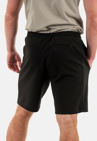 Shorts neri con vita elasticizzata, tasche laterali e una tasca posteriore con zip, in un tessuto leggero e liscio.