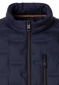 Granatowa pikowana kurtka z wyściełanym kołnierzem, centralnym zamkiem błyskawicznym oraz pionową kieszenią na zamek błyskawiczny na klatce piersiowej z czarnymi i brązowymi akcentami.