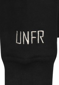 Černá ponožka s žebrovanou texturou, na horní straně s bílými vyšitémi písmeny tvořícími nápis "UNFR". Jednoduchý a monochromatický design.