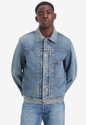 Svetlo modra jeans jakna z gumbi spredaj, koničastim ovratnikom, žepom na prsih in stranskima žepoma. Oprana površina z vidnimi šivi.