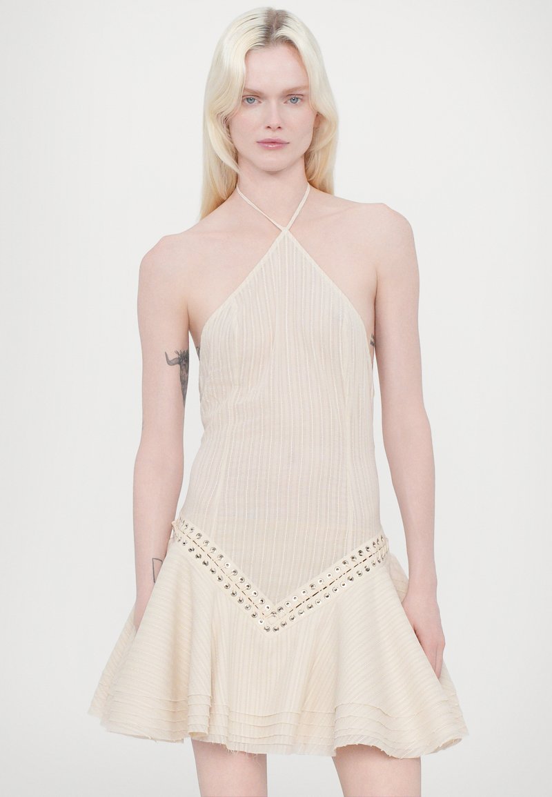 Light beige halter dress with vertical stripes, a flared skirt, and metal accents along the hem, featuring a textured, layered design.