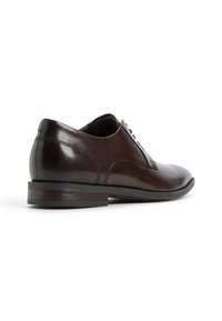 Scarpa da uomo in pelle marrone con una superficie liscia, forma arrotondata e tacco basso impilato. Presenta una chiusura con lacci e dettagli di cucitura sottili.