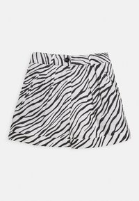 Short taille haute à rayures zèbre noir et blanc, passants de ceinture, bouton devant et détails plissés sur fond blanc.