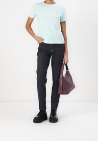 Lys mintgrøn kortærmet T-shirt, sorte slim-fit jeans, sorte snørrebukser og en mørk burgunder skuldertaske. Simpelt design, ingen mønstre.