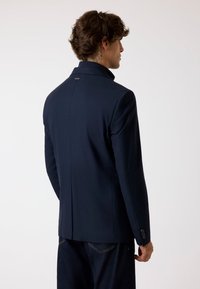 Marineblazer met hoge kraag, slim fit en twee-knopen mouwen. Glad stof met een subtiele glans en een klein logo-detail op de achterkant.