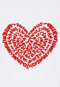 Design a cuore ricamato rosso composto da forme di testo varie su uno sfondo di tessuto bianco. Texture distintiva e motivo intricato.