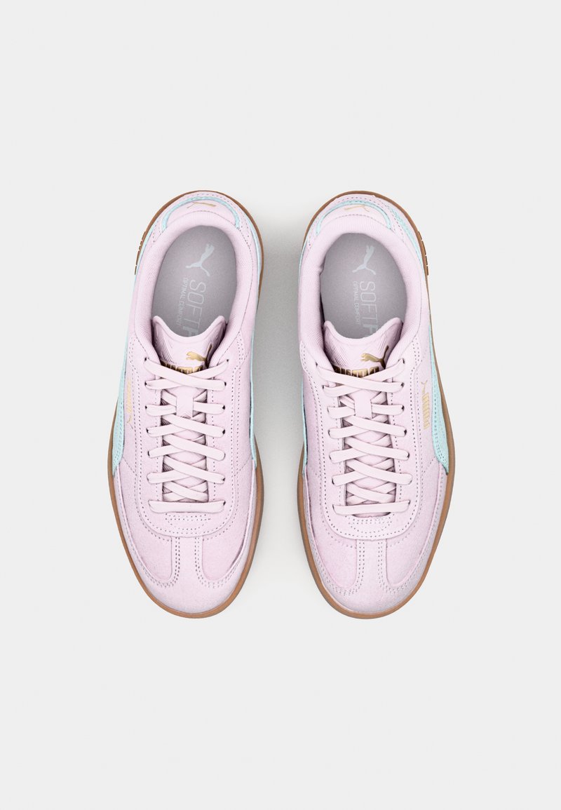 Sneaker rosa chiaro con una texture liscia, accenti blu discreti, lacci piatti e una suola in gomma marrone. Sottopiede SoftFoam visibile.