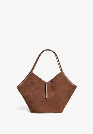 Sac tote en suede marron avec des garnitures en cuir et une fermeture à fine sangle, présentant une forme douce, large et légèrement anguleuse.