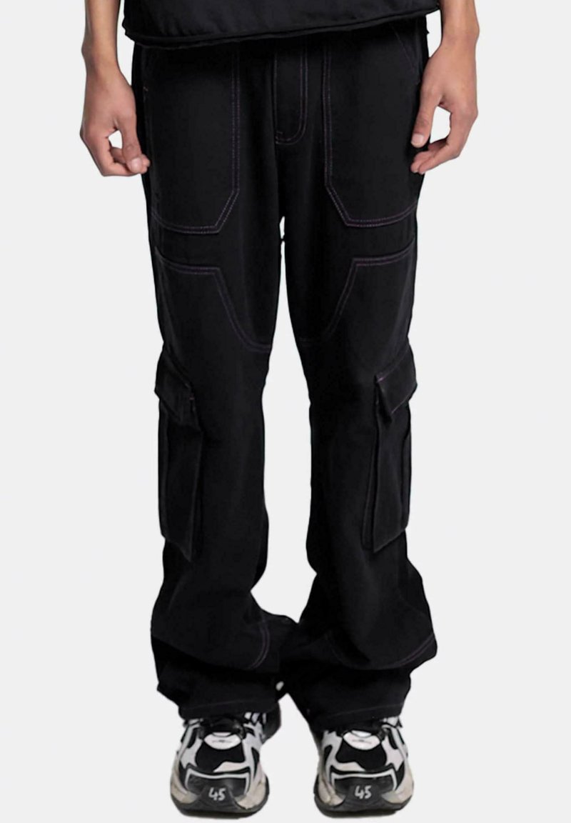 Pantalons cargo noirs avec des coutures violettes, plusieurs poches latérales, une coupe décontractée et une texture lisse, associés à des baskets noires et blanches.
