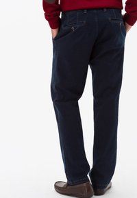 Pantaloni blu navy in stoffa, caratterizzati da un design dritto, due tasche posteriori con chiusura a bottone e dettagli di cucitura visibili.