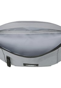 Borsetta grigia realizzata in tessuto resistente con un interno liscio e foderato. Presenta una zip nera e un'etichetta con marchio all'esterno.
